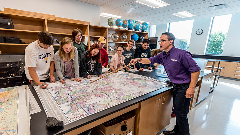 earth science students looking at map with instructor