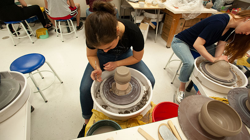 students working at a pottery wheel