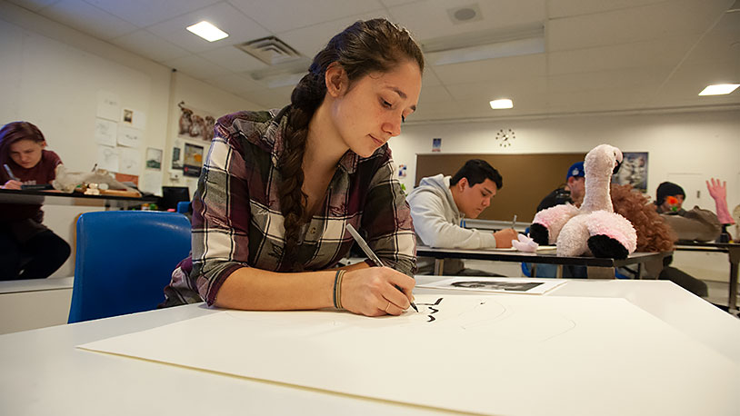 female student drawing with a pen
