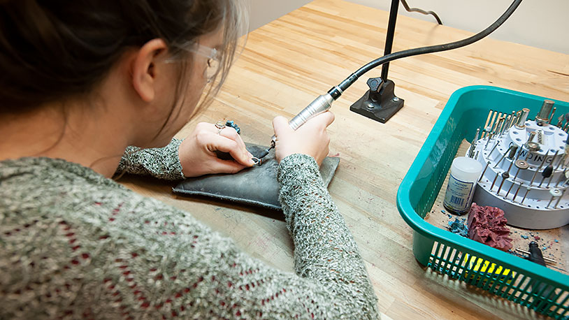 student using a dremel tool on a piece of jewelry