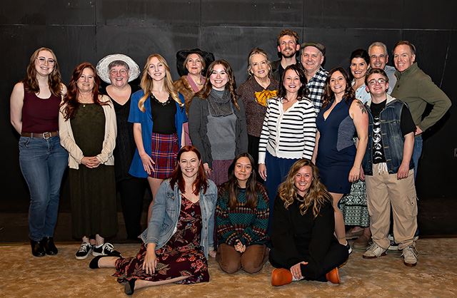 Group portrait of the cast and crew of Calendar Girls posing in front of a the Blackbox Theatre.
