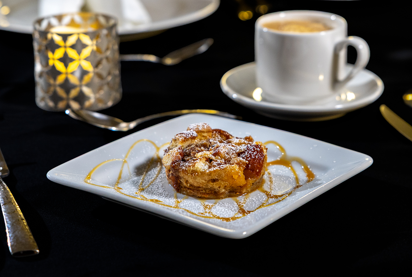 bread pudding with a caramel drizzle pictured on a white plate