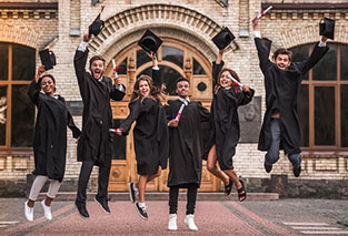 graduates jumping up in front of college
