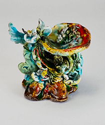 an ornate clay figure painted in greens and blues