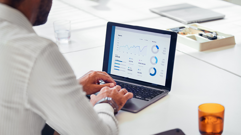 A person working on a laptop displaying a business analytics dashboard with various charts and graphs.