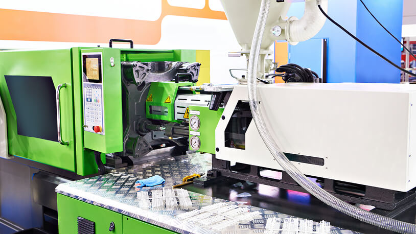 A green and white injection molding machine, showcasing the work of an injection molding technician.